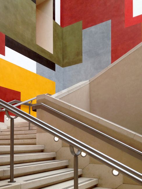 A modern indoor staircase with vibrant geometric wall patterns.