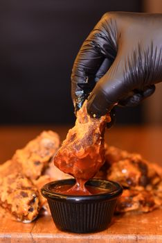 Close-up of crispy chicken wing dipped in hot sauce, perfect for food lovers.