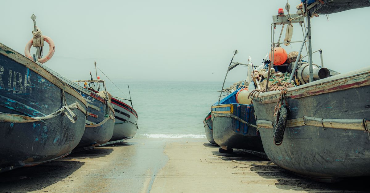 Traditional fishing boats lined up at Imsouane Beach in Morocco, ready for a day at sea.