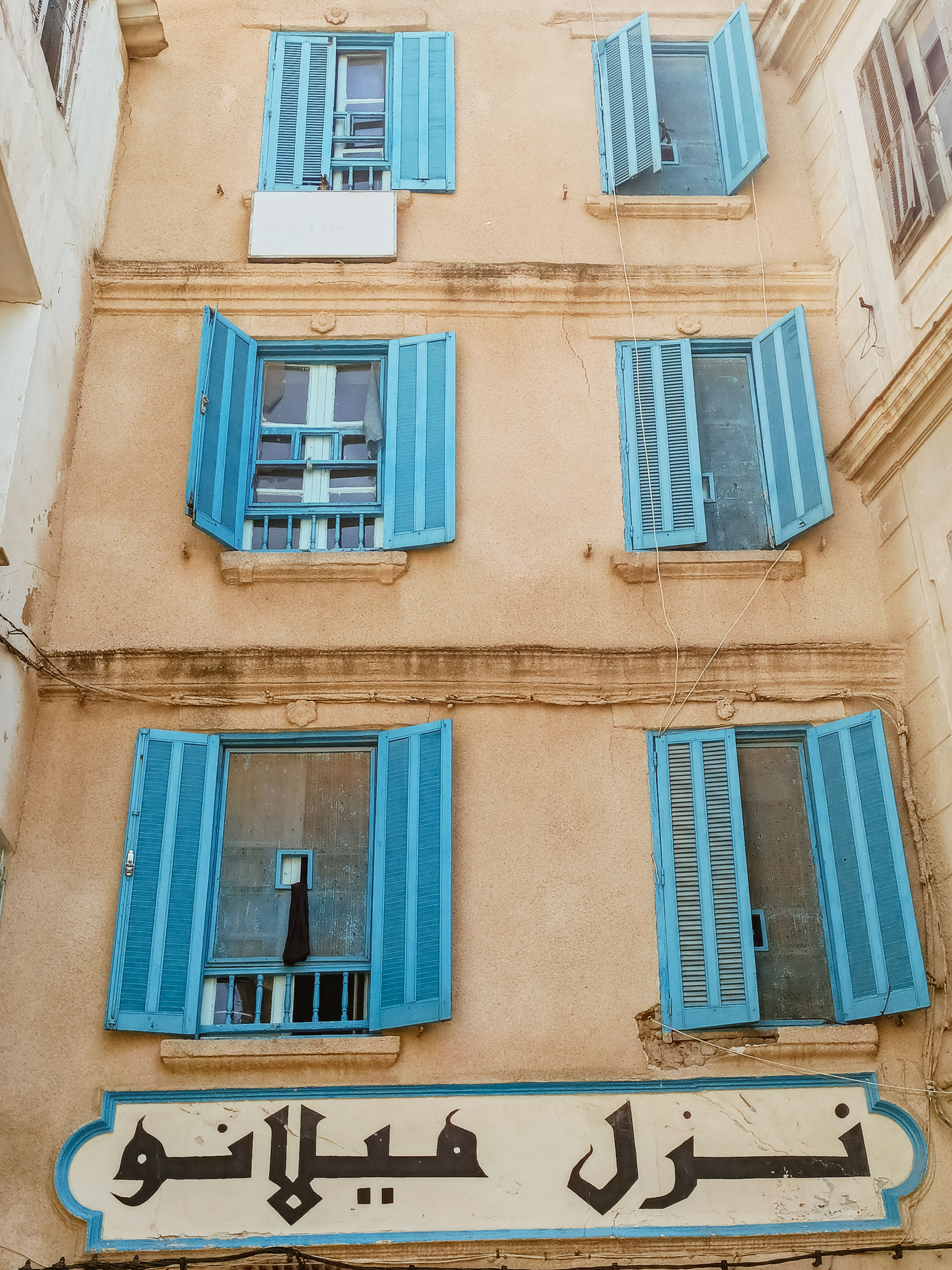 A building with blue shutters and arabic writing · Free Stock Photo
