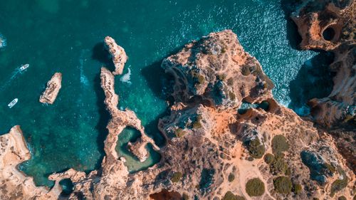 Free Stunning aerial shot of rocky coastal formations with vibrant turquoise waters and boats. Stock Photo
