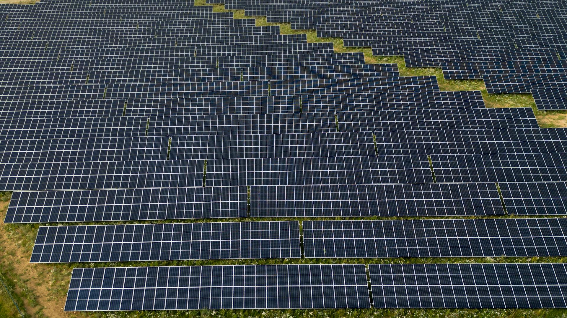 Aerial photograph capturing the geometric layout of a large solar panel farm. Sustainable energy focus.