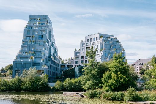 Elegant modern buildings near a river in Rennes, France, showcasing urban sophistication.