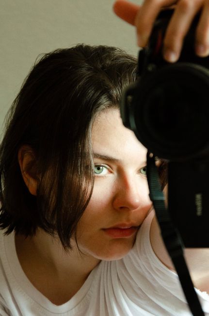 Candid self-portrait of a young woman using a camera indoors.
