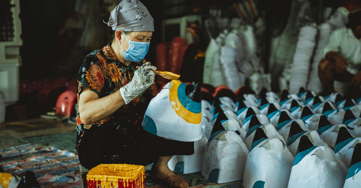 Skilled artisan painting colorful masks amidst a bustling market setting, highlighting traditional craftsmanship.