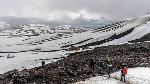 Free Adventurers hiking through the snowy mountains of Landmannalaugar, Iceland, showcasing rugged terrain and winter exploration. Stock Photo