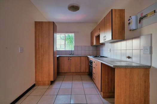 Minimalist kitchen design featuring wooden cabinets and ample natural light from a window.