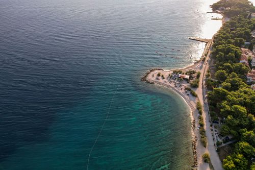 Free A stunning aerial view of a serene coastal beach with clear waters and lush greenery. Stock Photo