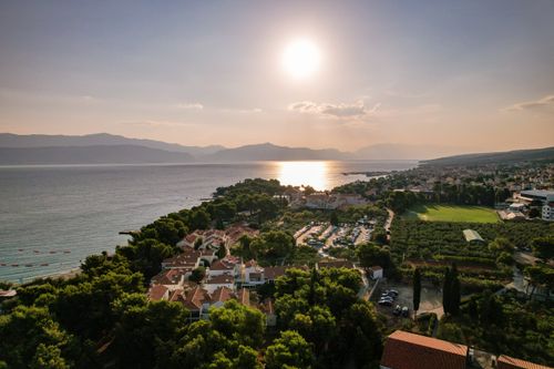 Free Stunning aerial view of a coastal Mediterranean town with the sun setting over the sea. Stock Photo