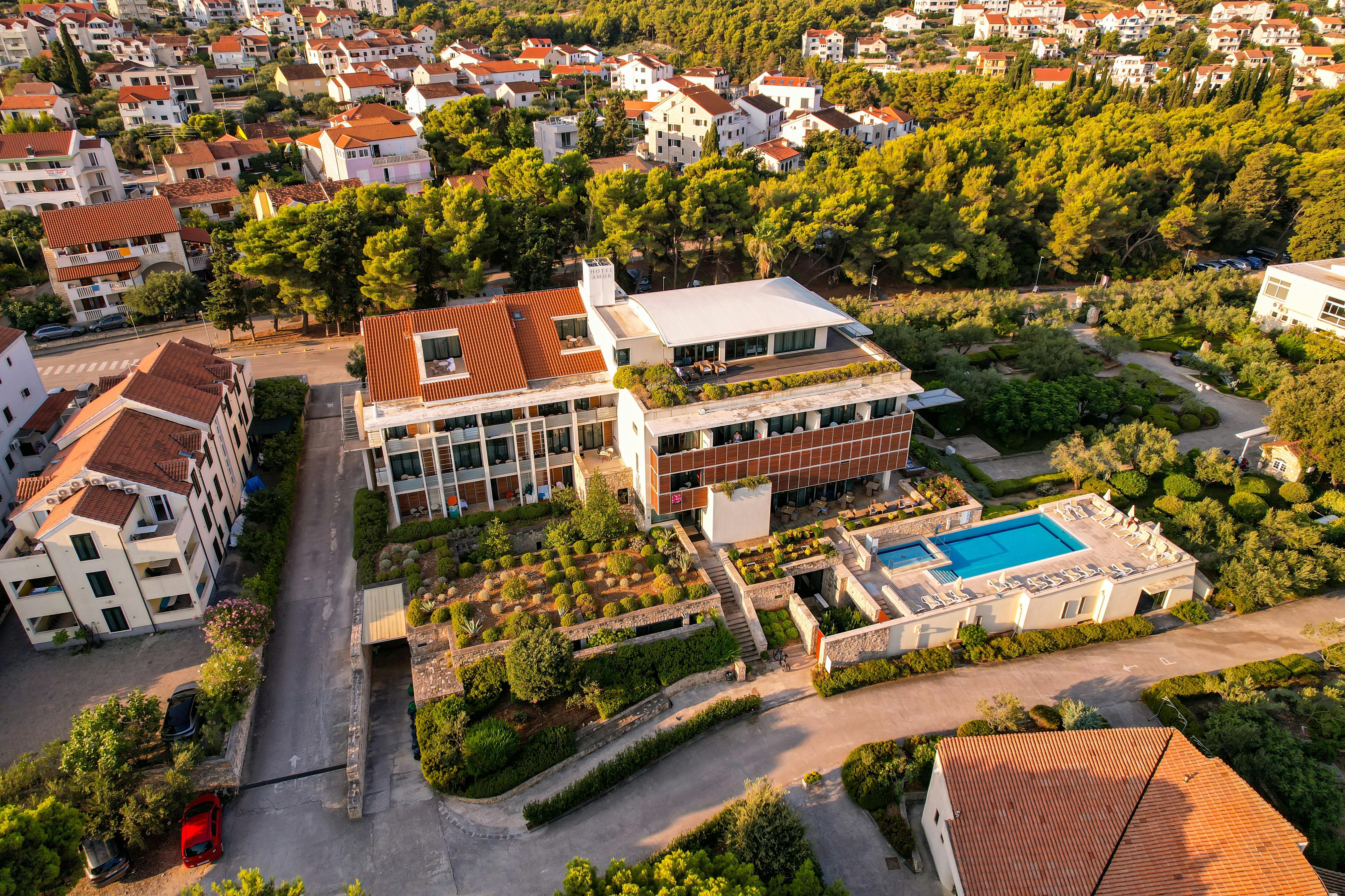 Discover a stunning modern villa with a pool, surrounded by lush greenery and traditional homes. - Photo by Vladimir Srajber on Pexels