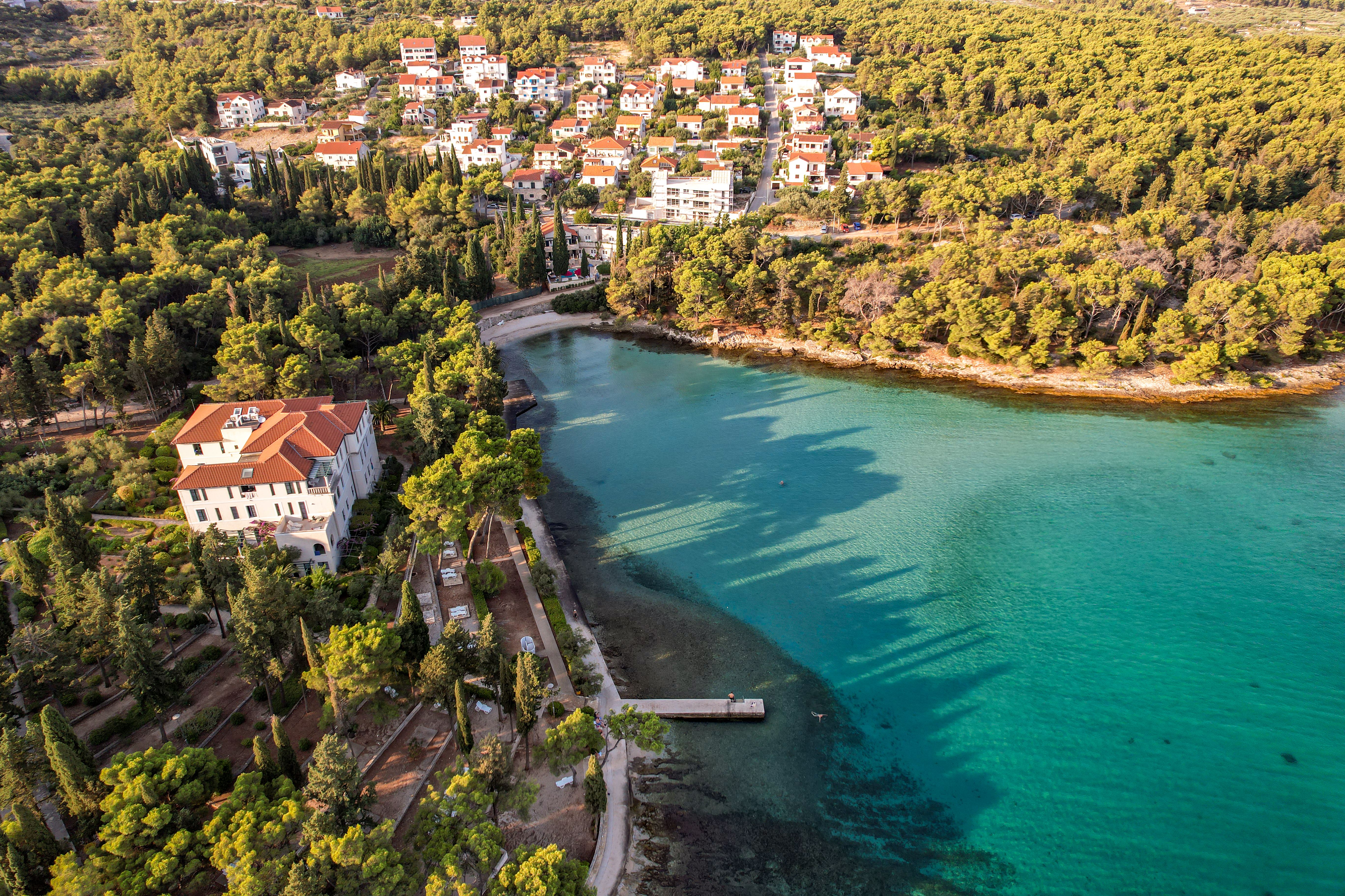 Aerial view of a picturesque coastal town surrounded by dense forests and clear turquoise waters.