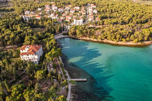 Aerial view of a picturesque coastal town surrounded by dense forests and clear turquoise waters.