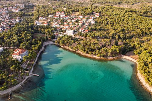 Free Explore the beauty of a coastal village and turquoise bay surrounded by lush forests from above. Stock Photo