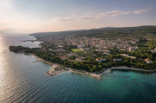 Free Stunning aerial view of a coastal town showing beaches, forest, and clear sea under a summer sky. Stock Photo