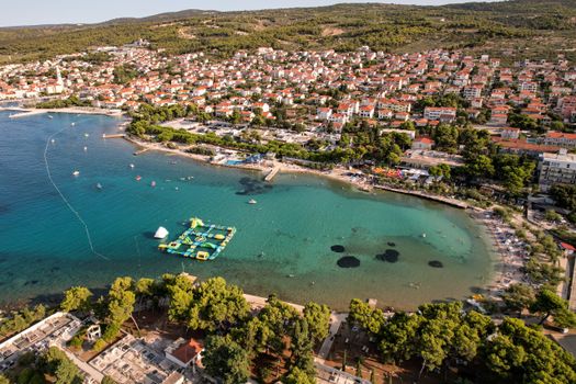 Aerial view of a vibrant coastal town, featuring a marina and clear turquoise waters perfect for vacation.