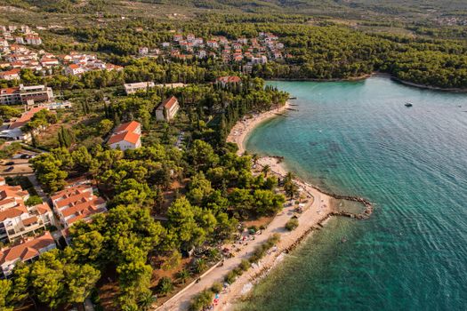 A beautiful aerial view of a coastal town with lush greenery and a calm sea in summer.