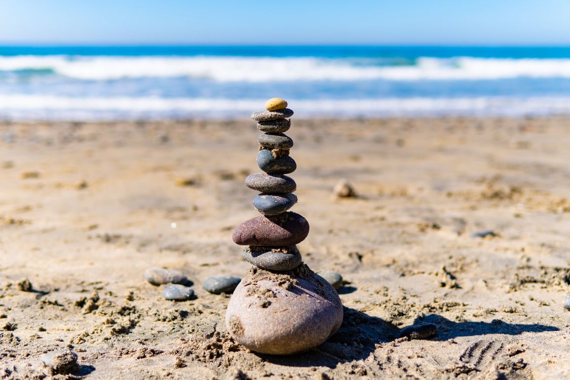 A stack of rocks on the beach with the ocean in the background · Free ...