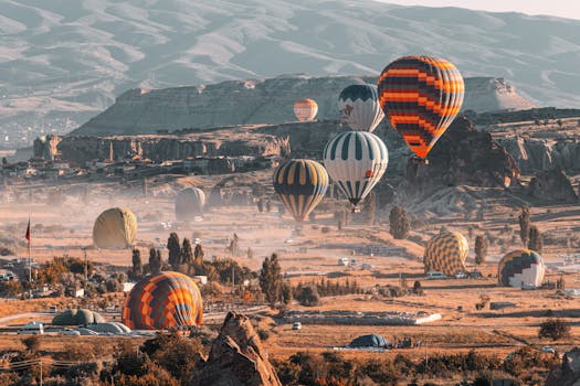 Stunning view of hot air balloons flying over Cappadocia's unique landscape at sunrise.