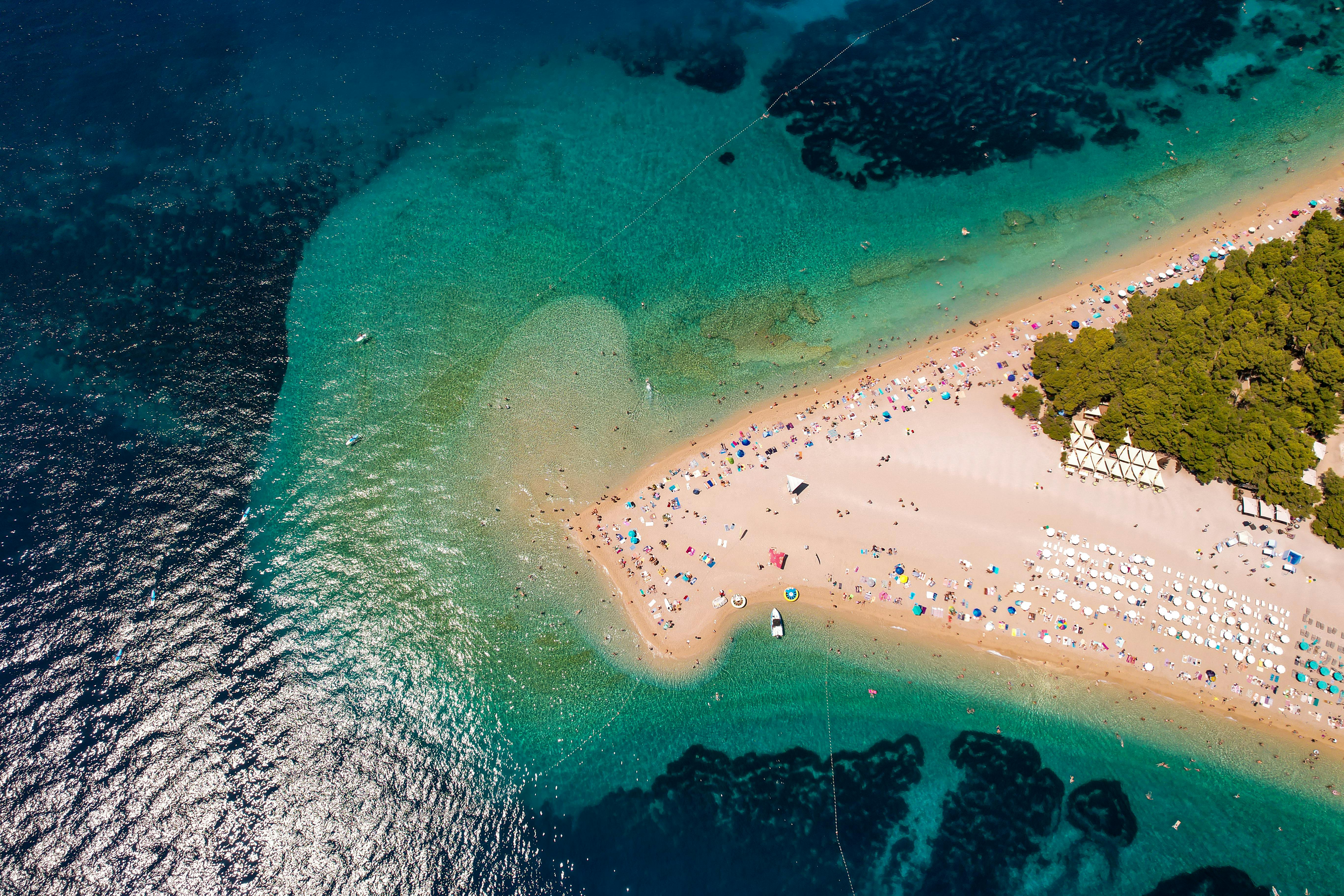 Zlatni Rat beach pebble spit extending into turquoise Adriatic Sea under bright midday sunshine from Bol harbor