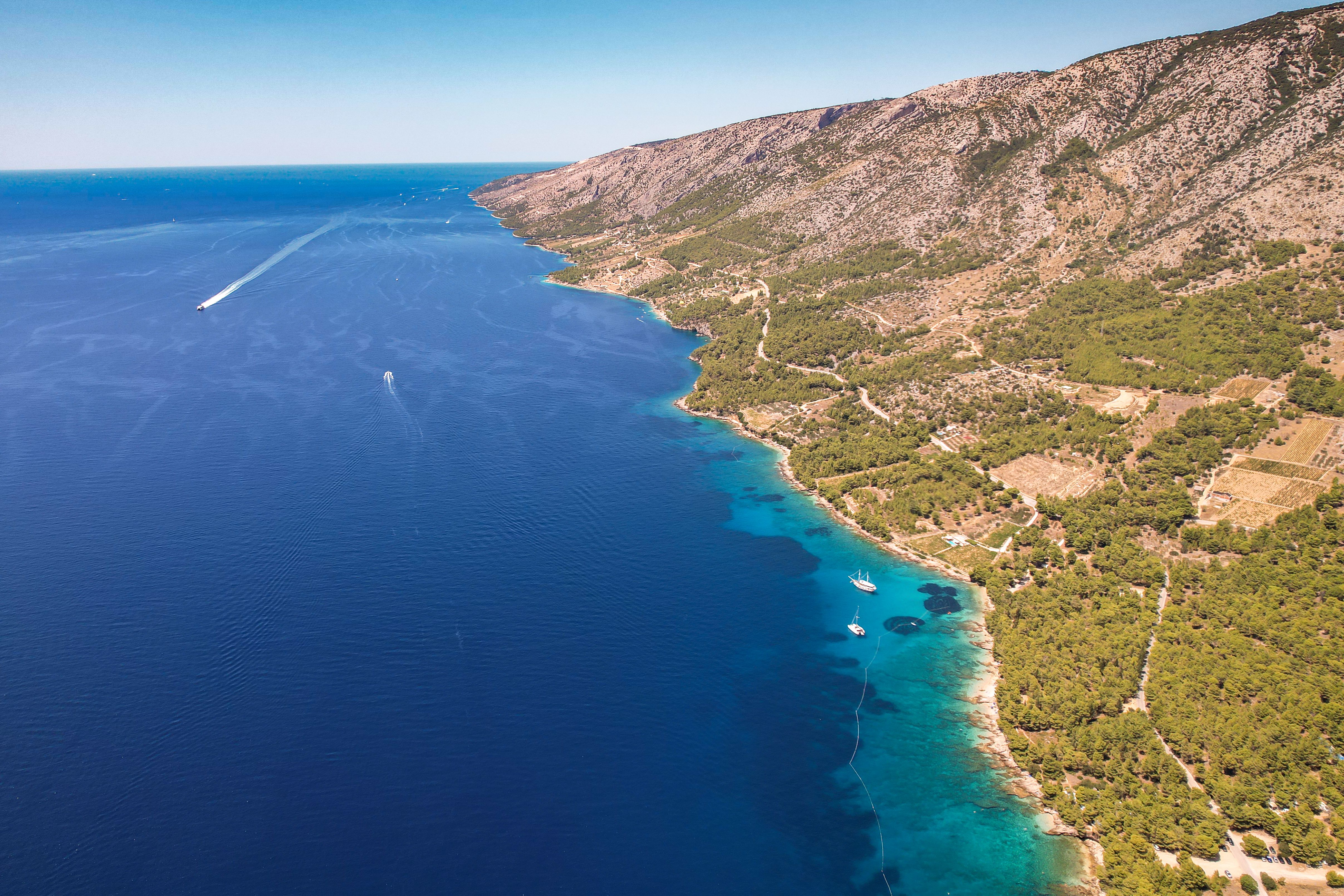 Stunning aerial view of a coastline with blue ocean and lush greenery, perfect for summer travel visuals.
