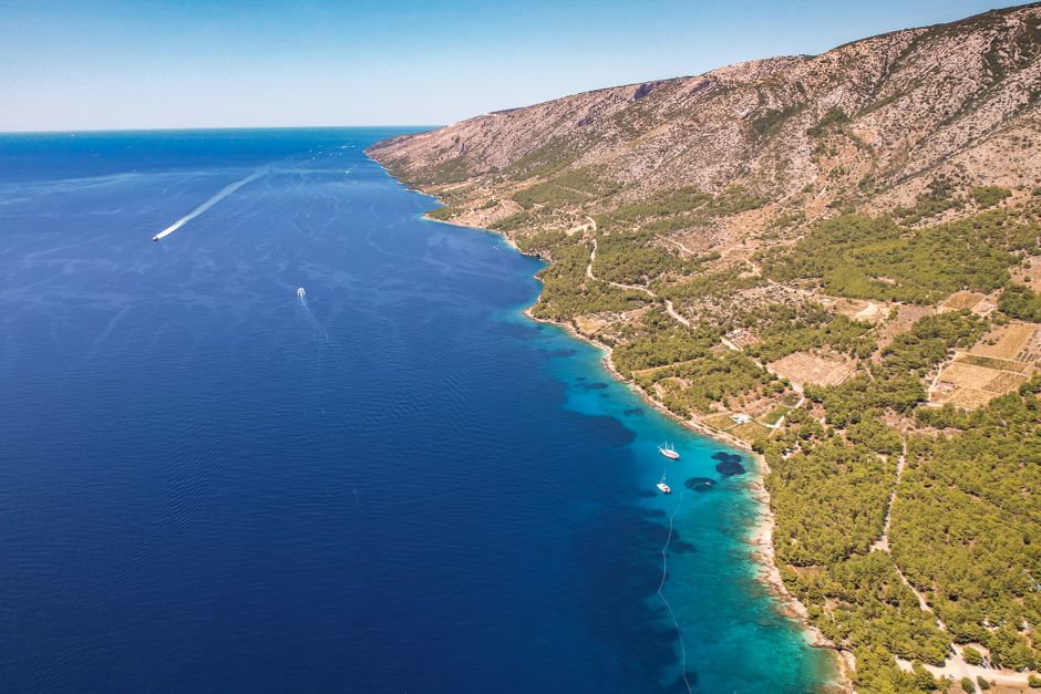 Stunning aerial view of a coastline with blue ocean and lush greenery, perfect for summer travel visuals.