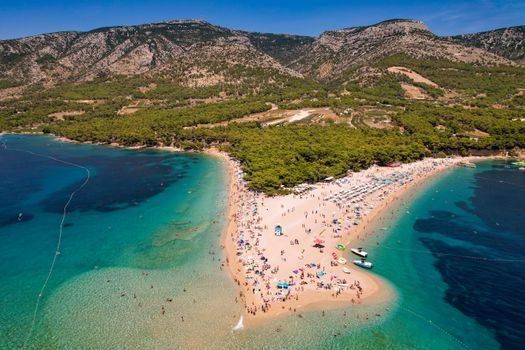 Vibrant aerial view of Zlatni Rat beach, Croatia with turquoise waters and lush greenery.