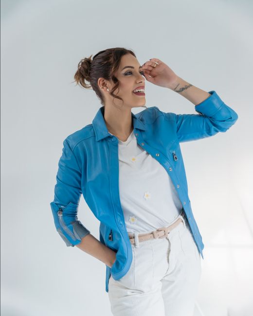Portrait of a young woman smiling confidently in a blue jacket, expressing joy and style.
