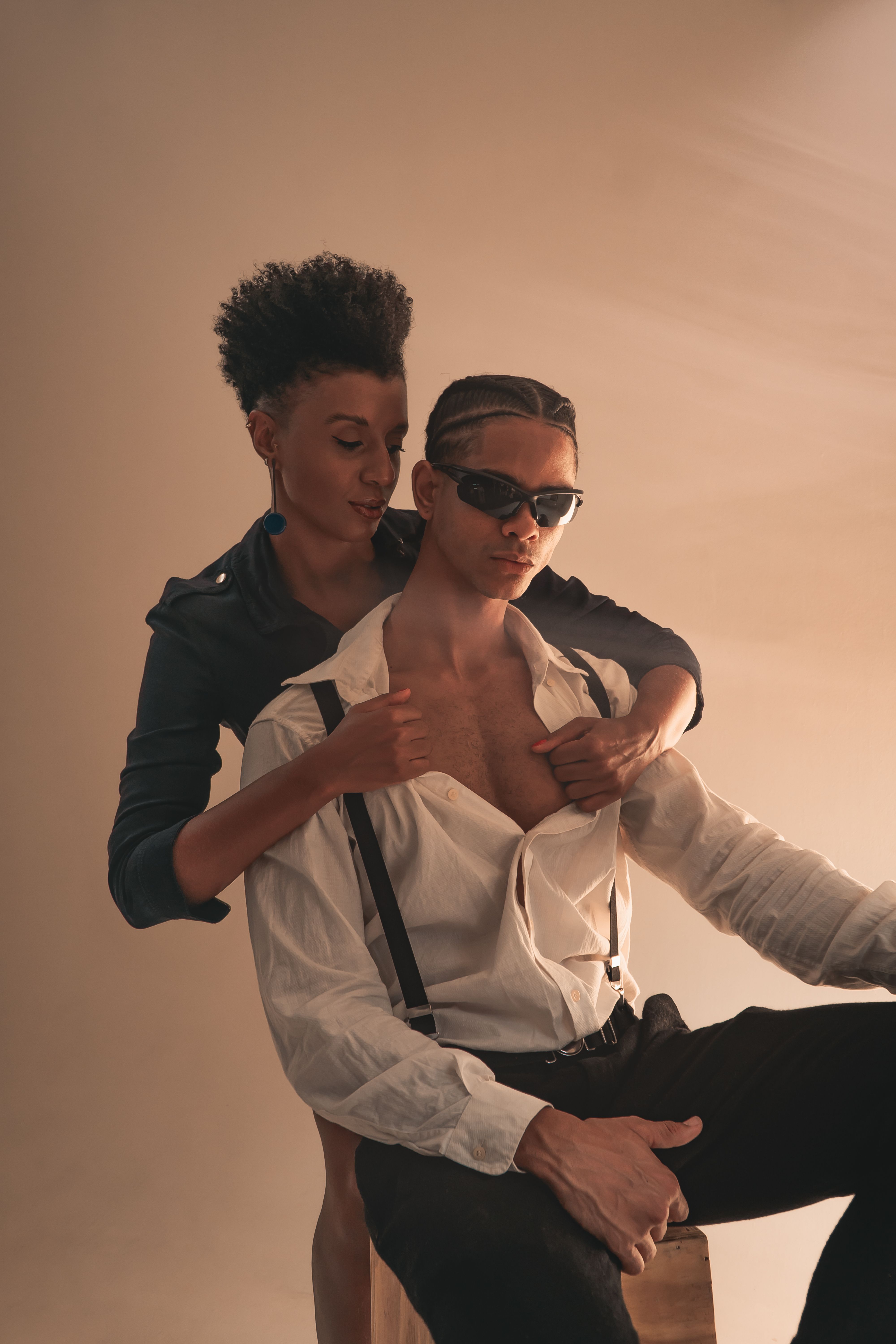 A fashionable couple poses intimately in a studio setting, exuding modern romance and style.