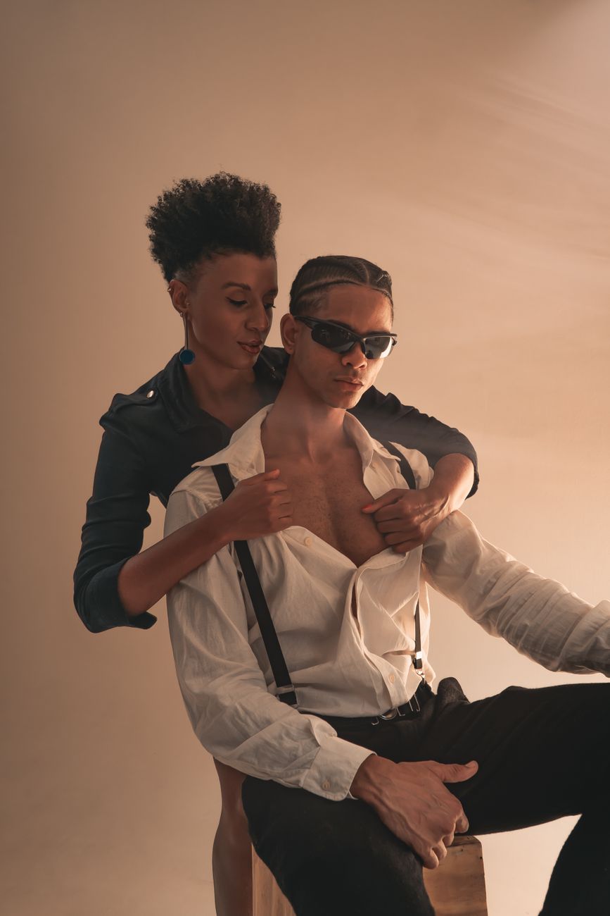 A fashionable couple poses intimately in a studio setting, exuding modern romance and style.