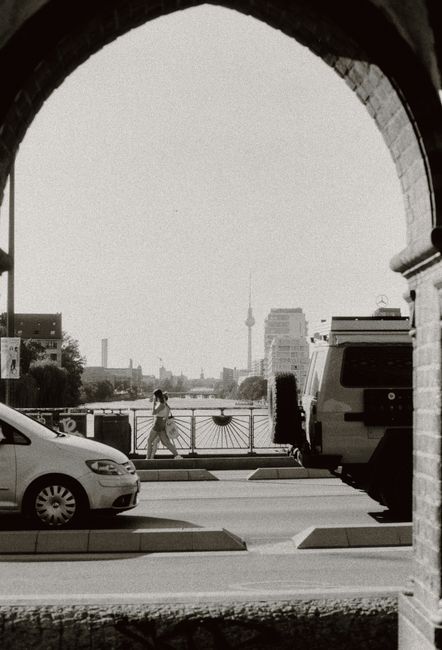Monochrome image capturing Berlin's urban life with cars, pedestrians, and the iconic TV Tower.