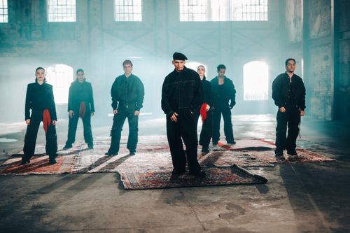 Free Adults in a warehouse setting with dramatic lighting, standing on rugs. Stock Photo