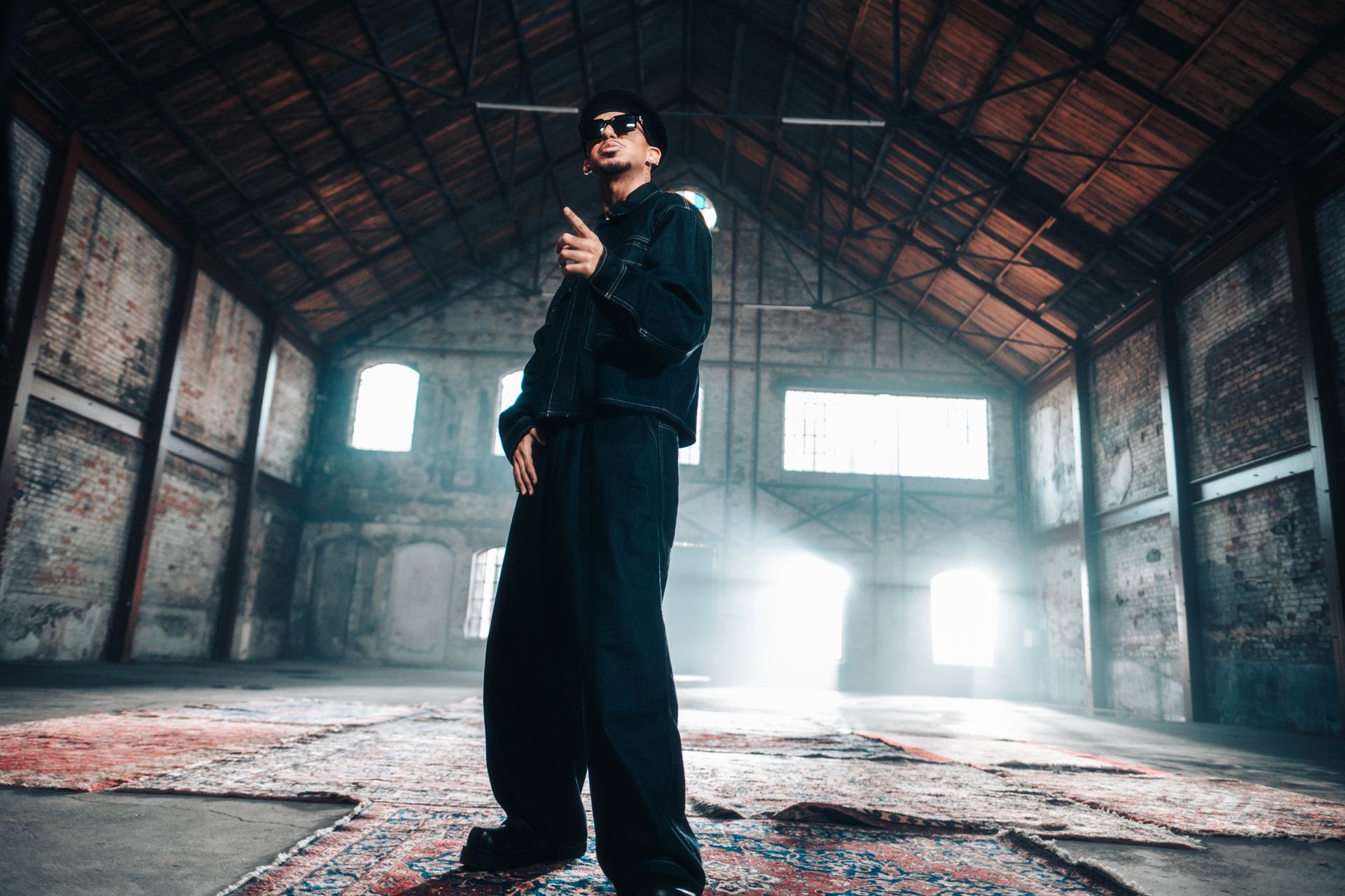 Urban fashion portrait of a man in a dramatic industrial warehouse setting with streaming light.