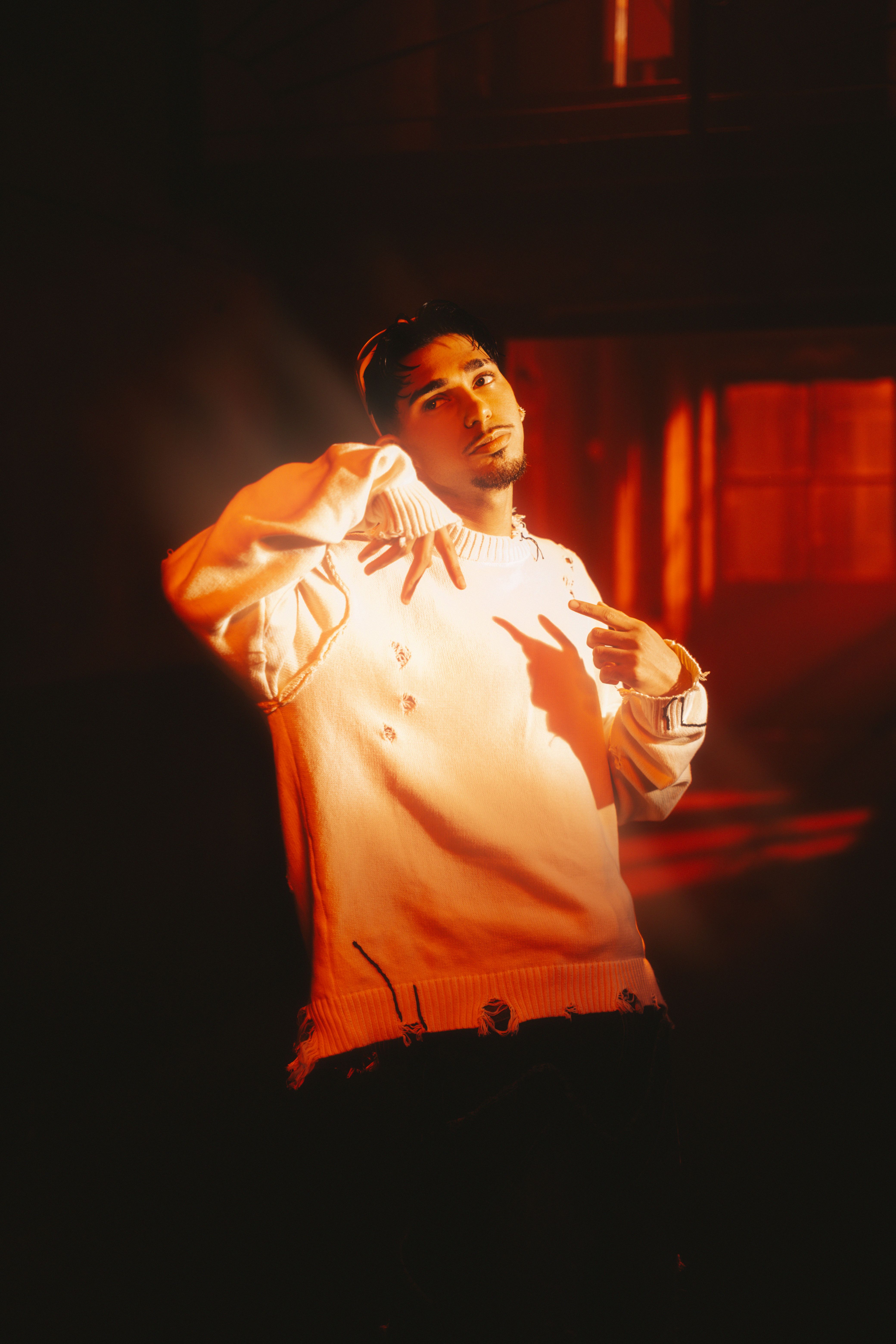A man in a white shirt standing in front of a red light · Free Stock Photo