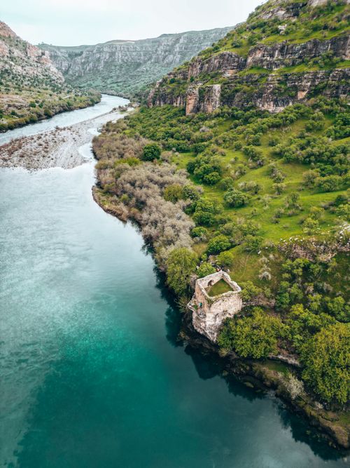 Free Scenic aerial shot of a river and lush green cliffs in Güçlükonak, Türkiye. Stock Photo