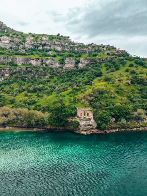 Free Beautiful hillside view with rich greenery over a clear turquoise river in Güçlükonak, Şırnak, Turkey. Stock Photo