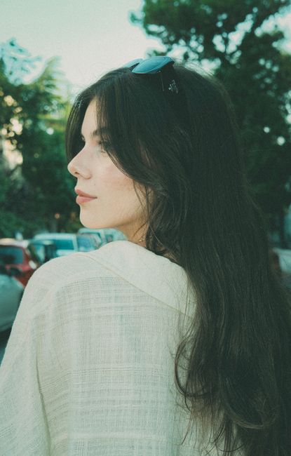 Portrait of a brunette woman outdoors in a summer setting, showcasing elegant fashion and natural beauty.
