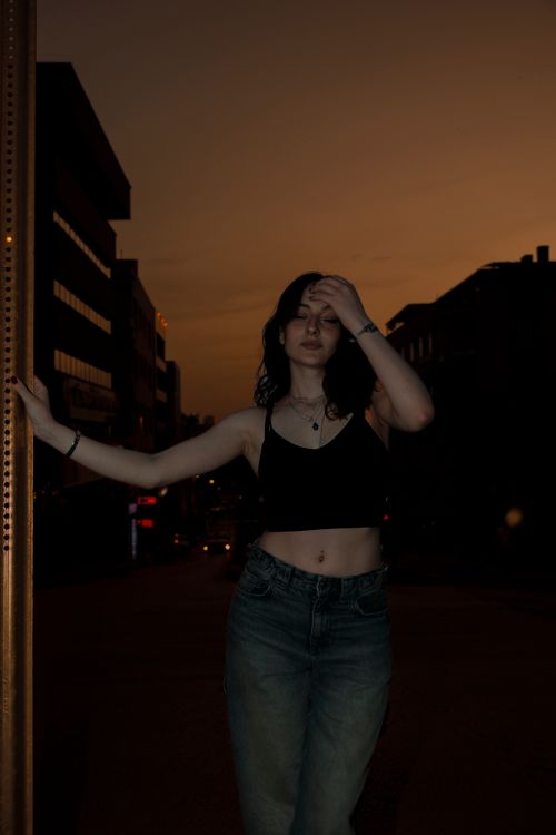Free A serene portrait of a woman in an urban setting at sunset, exploring quiet contemplation. Stock Photo