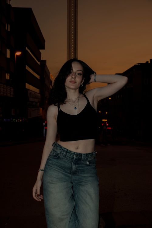 Free A fashionable woman poses confidently on a city street at dusk, showcasing urban style. Stock Photo
