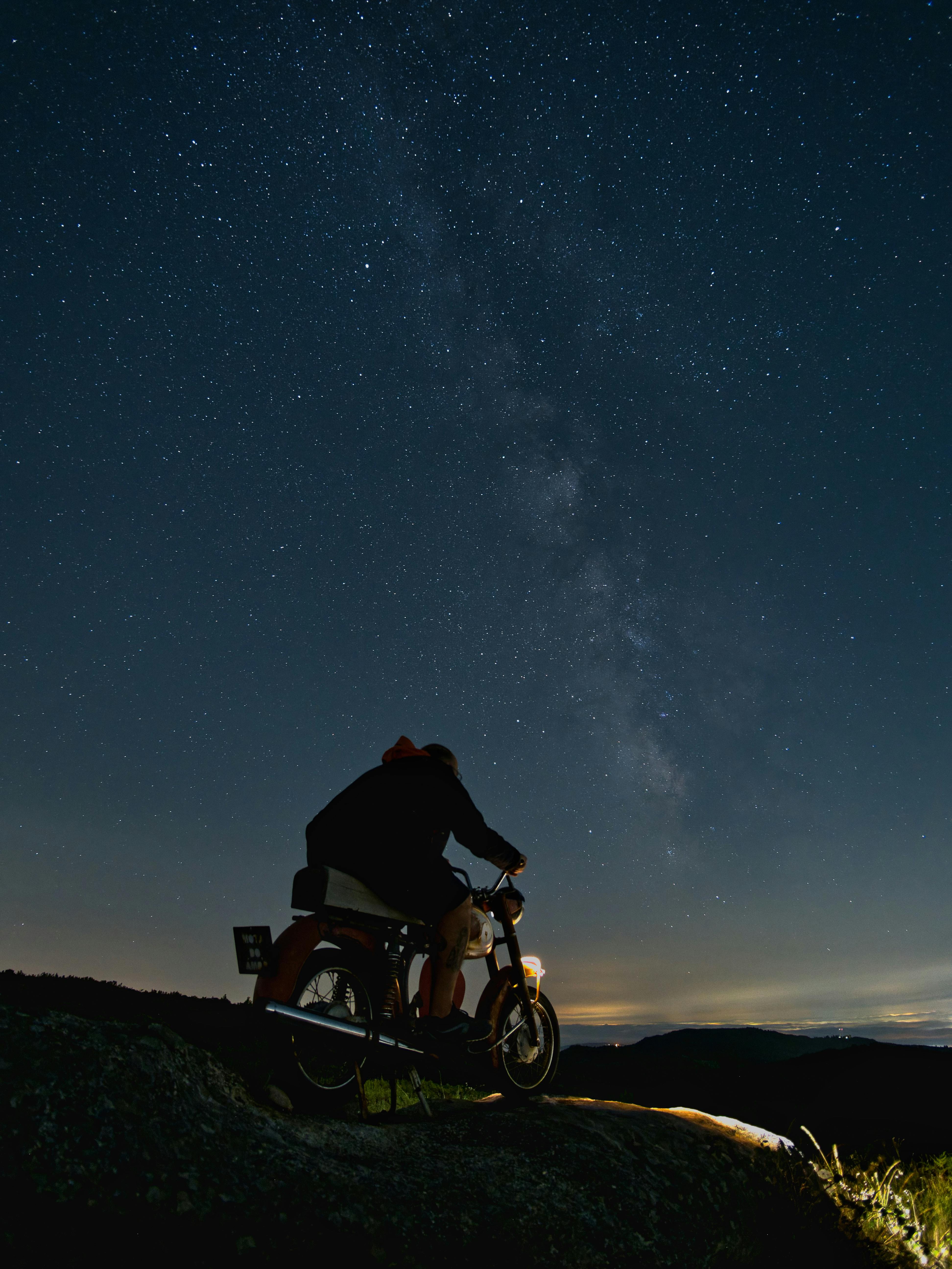 a person on a motorcycle looking up at the stars