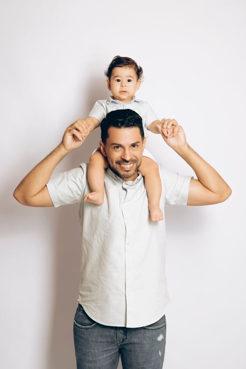 Free Father with his child on shoulders, both smiling, loving indoor moment. Stock Photo