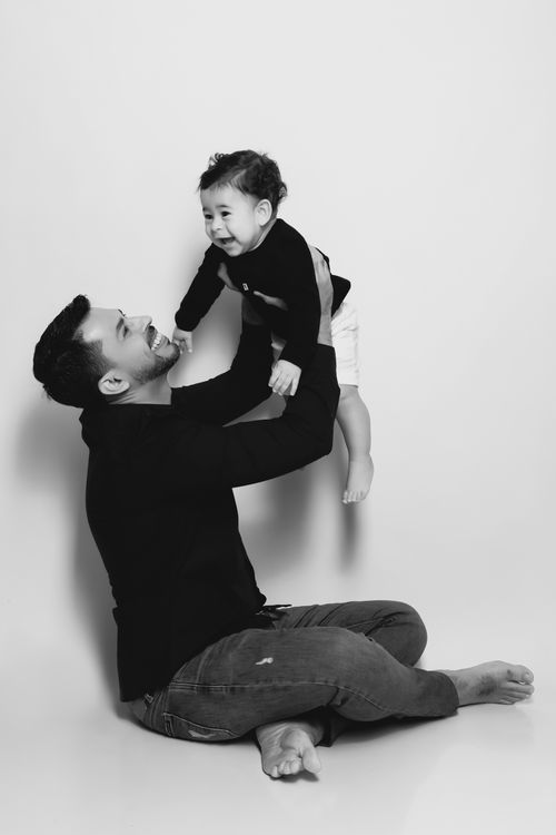 Free Joyful father lifting his son in a heartwarming black and white portrait indoors. Stock Photo