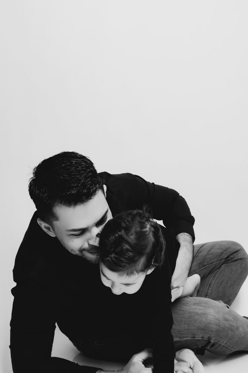 Free Heartwarming black and white photo of a father lovingly embracing his child indoors. Stock Photo