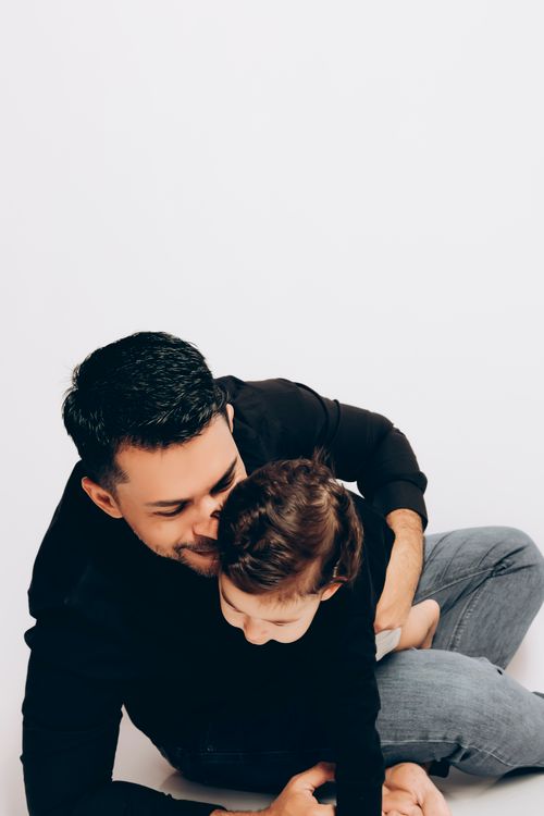 Free A father and child embrace and play joyfully indoors, symbolizing love and togetherness. Stock Photo