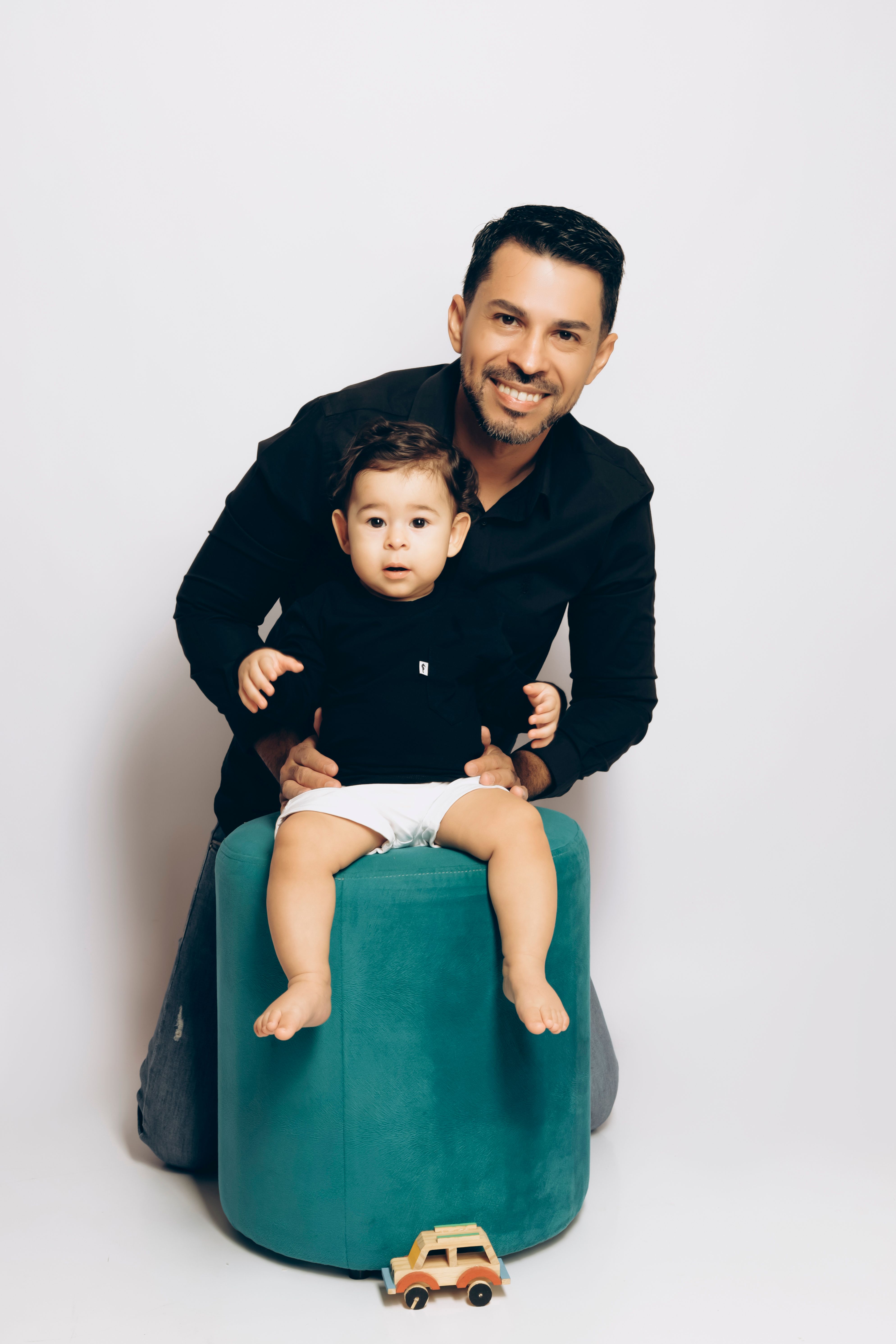 Father and son bonding in an indoor portrait with a toy car adding playful touch.