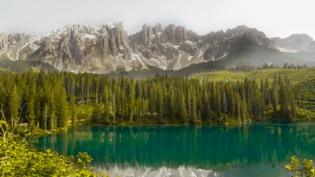 Stunning landscape of the Dolomite Mountains and serene lake reflecting the sky, perfect for travel enthusiasts.
