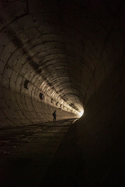 A lone silhouette standing in a dimly lit tunnel, creating a dramatic and moody atmosphere.