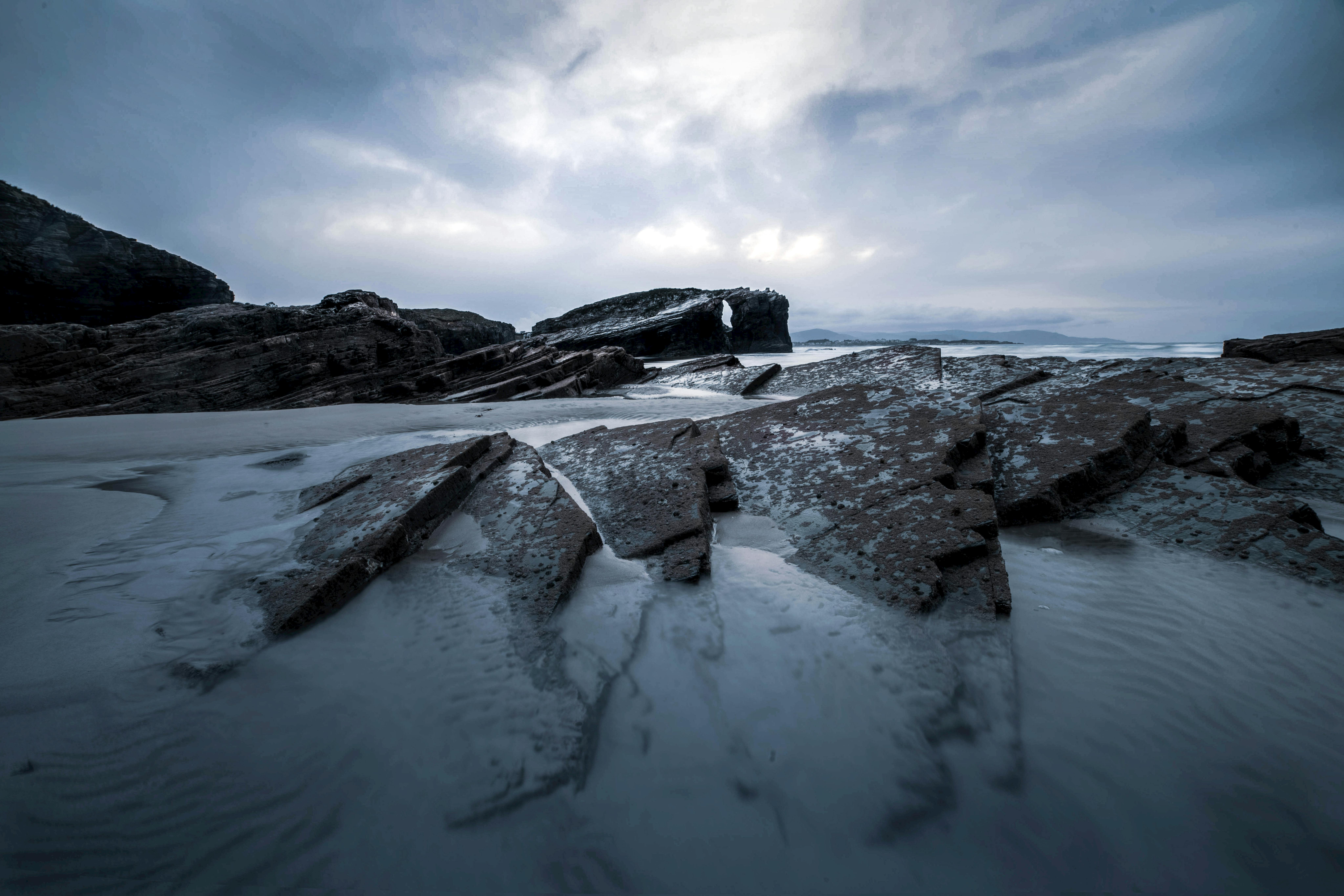 A serene winter seaside landscape with dramatic rock formations and soft lighting.