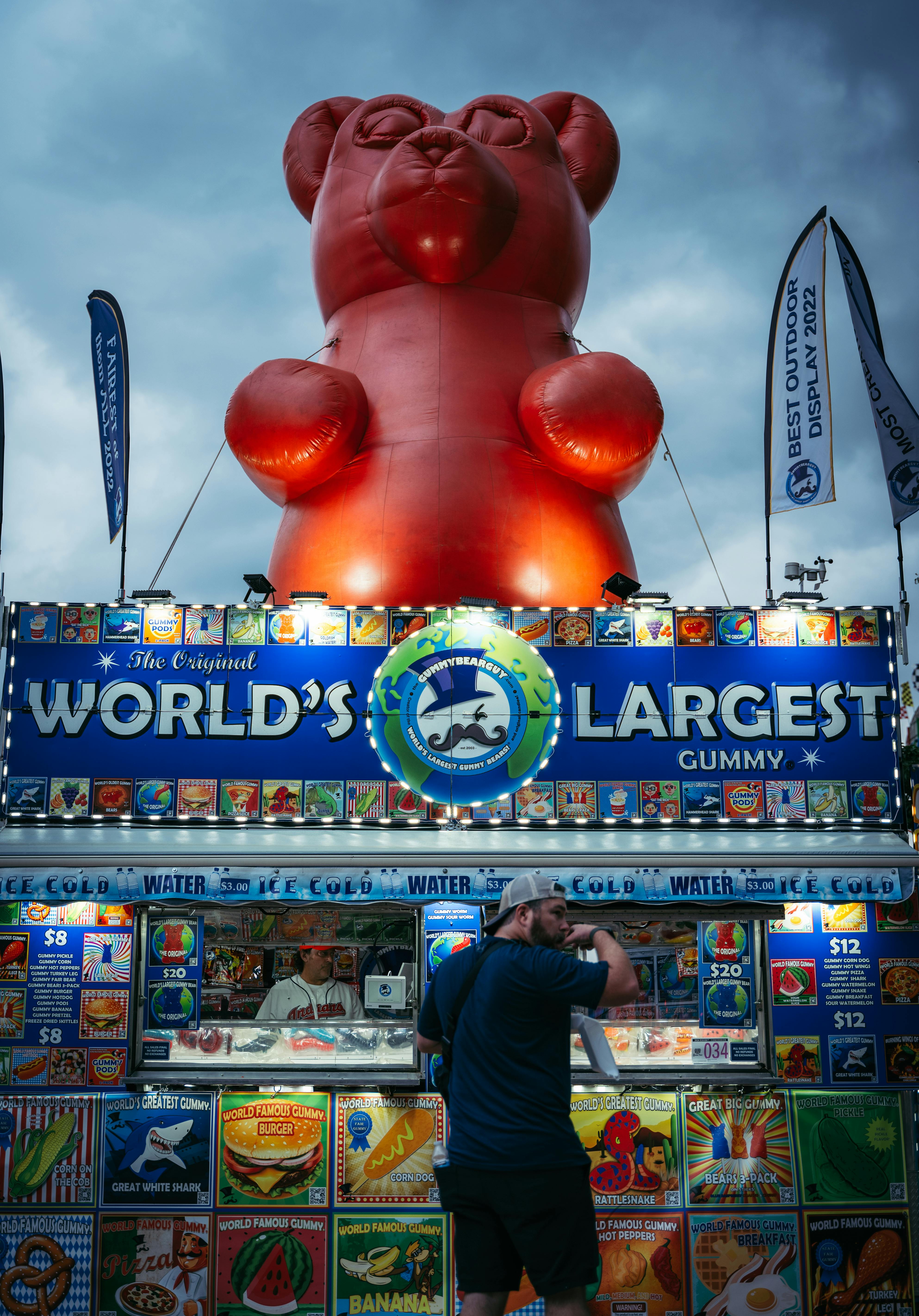 a man standing in front of a giant teddy bear