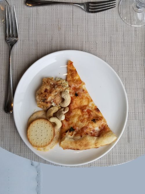 Free Cheese pizza slice with crackers and nuts on a white plate. Perfect for a quick meal or snack. Stock Photo