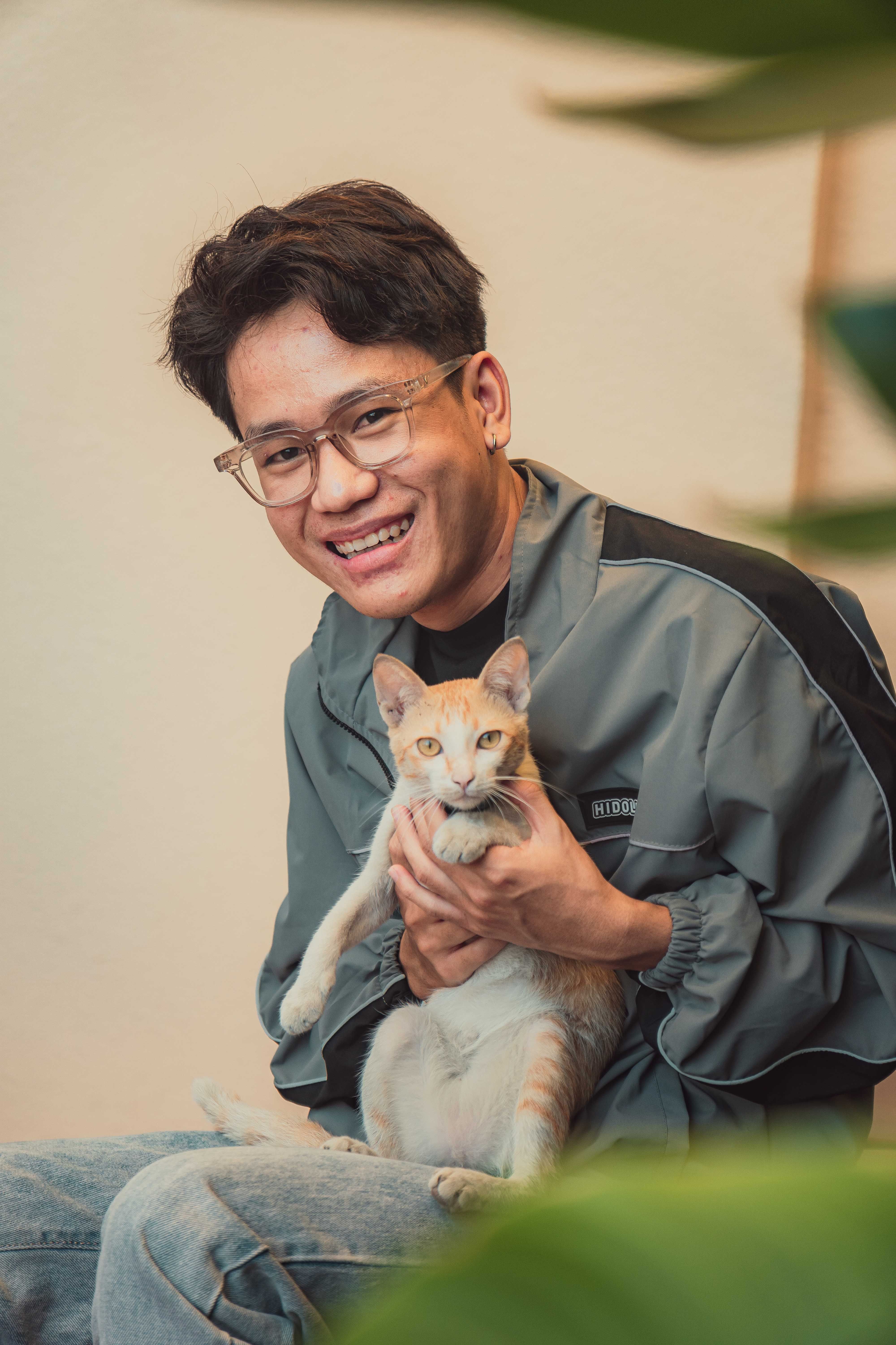 Joyful portrait of a man holding a cat indoors, capturing a moment of warmth and affection.